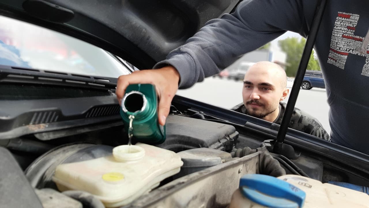 Mechanic topping up coolant during a service